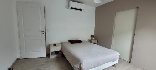 een witte slaapkamer met een bed en een deur bij Maison de ville avec terrasse et clim in Foucherans
