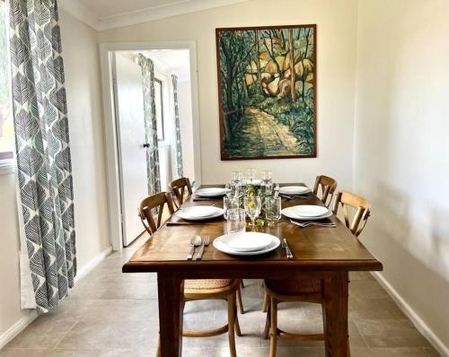 a dining room table with chairs and a painting on the wall at Wattle Cottage in Mandurama