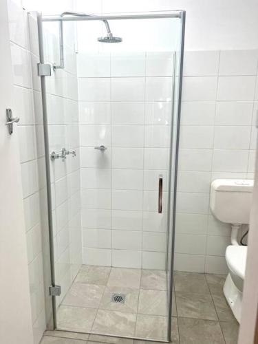a bathroom with a glass shower with a toilet at Wattle Cottage in Mandurama