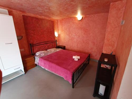 a small room with a bed with a red blanket at Azalea Garden Apartment With Mountain View in Kremasti