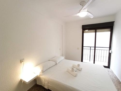 ベニドルムにあるApartamento Playa Benidormのベッドルーム1室(白いベッド1台、タオル2枚付)