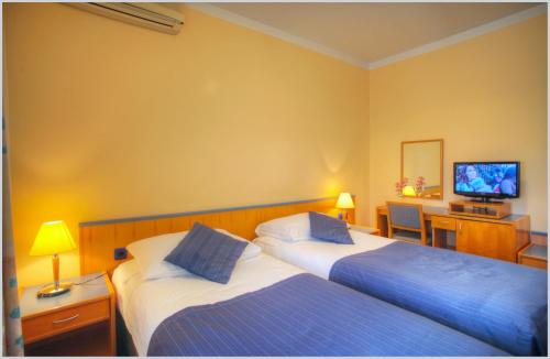 a hotel room with two beds and a television at Tamaris Rooms in Zadar