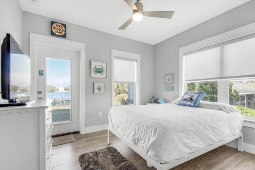 a bedroom with a bed and a tv and windows at Pelican at Sound Side in Fort Walton Beach