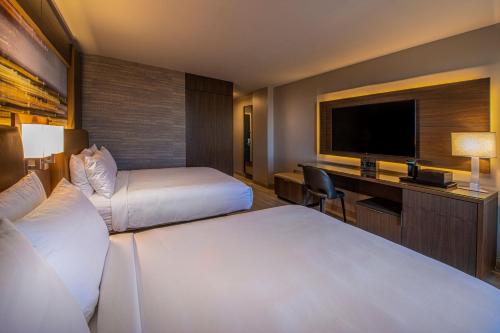 a hotel room with two beds and a desk and a television at Wichita Marriott in Wichita