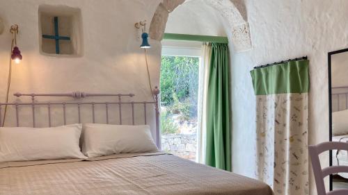 Schlafzimmer mit einem Bett und einem Fenster in der Unterkunft Lacinera Trulli e Lamie in Ostuni