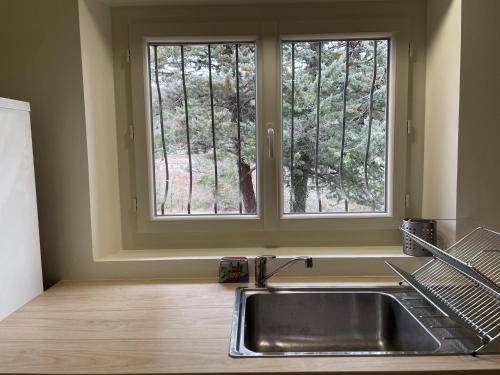 une cuisine avec un évier et une fenêtre dans l'établissement T3 rénové esprit vintage, au coeur du Verdon, à Montagnac