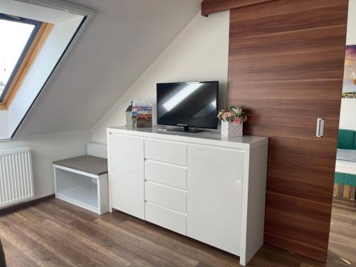 - un salon avec une télévision sur une commode blanche dans l'établissement Bella Wellness Apartman, à Hajdúszoboszló