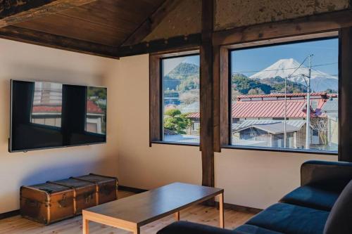 a living room with a table and three windows at MITSU-House in Nishikatsuracho