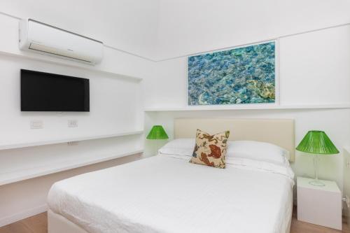 a white bedroom with a bed and a flat screen tv at Casa Piccola by Capri 5 Senses in Capri