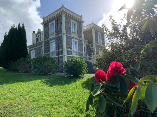 una casa grande con flores rojas delante de ella en Villa Auristela, en Navia