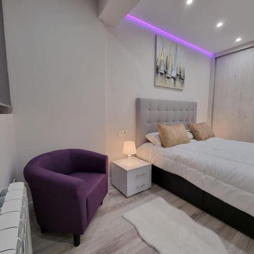 ein Schlafzimmer mit einem Bett und einem lila Stuhl in der Unterkunft Soho Boutique Tioda, Totalmente reformado junto a las estaciones, WIFI in Oviedo