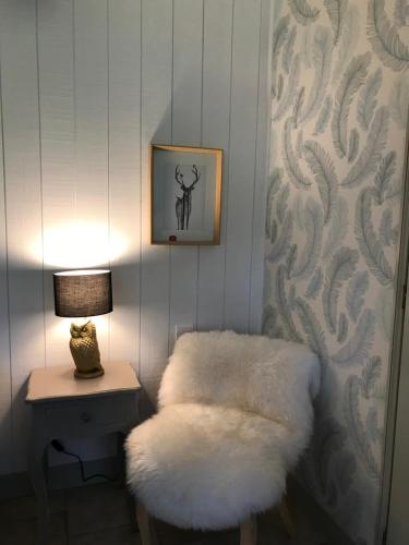 a room with a white stool and a table with a lamp at Les Fermes de Florence Bien être et nature in Les Champeaux