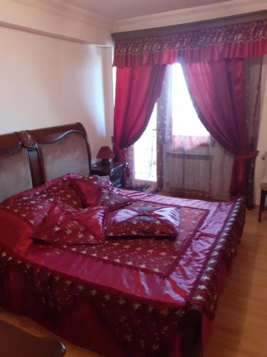 um quarto com uma cama com lençóis vermelhos e uma janela em Апартаменты с джакузи от 7 дней em Yerevan