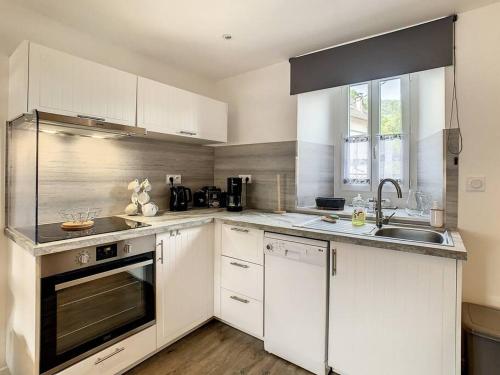 a kitchen with white cabinets and a sink at Happy HOME in Cierp