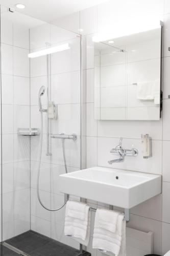 a white bathroom with a sink and a shower at Hotel Sursee in Sursee