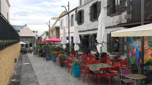 a patio with tables and chairs and white umbrellas at Le Barachois City in Saint-Denis