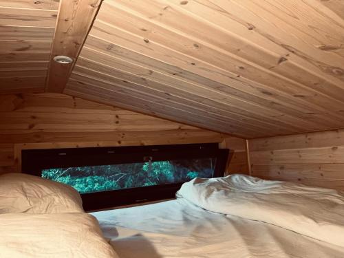 a bedroom with a bed and a tv in a wooden ceiling at The Grey Tiny in Chimay