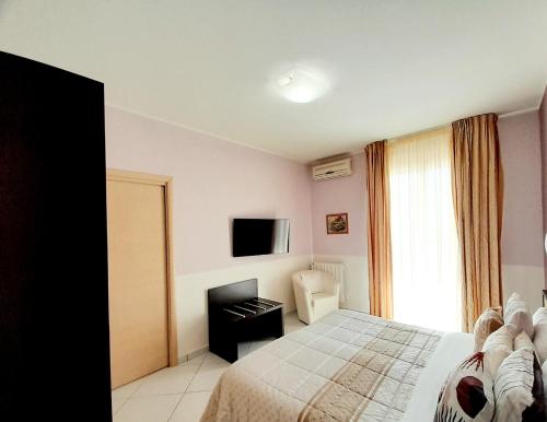 a bedroom with a bed and a television and a chair at Appartamento Castel Sant'Angelo in Licata