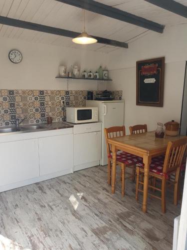 une cuisine avec une table et des chaises et un micro-ondes dans l'établissement La maisonnette 301, à Saint-Ouen-en-Belin