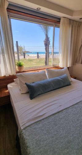 Una cama grande en un dormitorio con una ventana grande. en Dor on the beach, en Dor