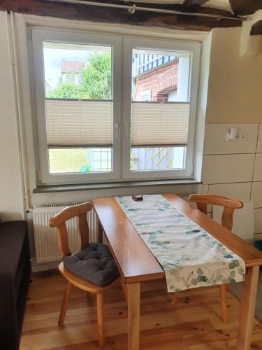 a table and two chairs in a room with two windows at Fachwerk zum Entspannen, max. 3P in Bad Emstal