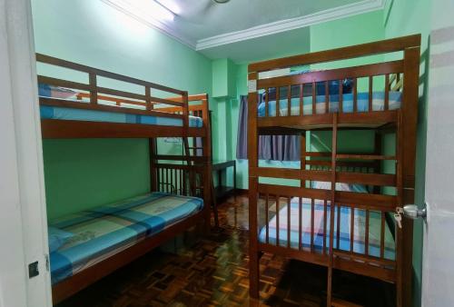 two bunk beds in a room with green walls at 3 Rooms 2 parking 10pax PSR Comfy Sofa&Bed near MRT Eateries McD in Seri Kembangan