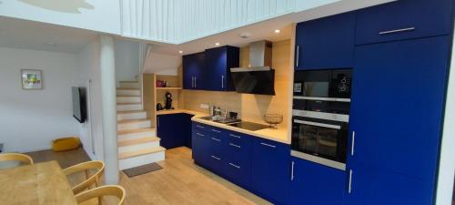 uma cozinha com armários azuis e uma escadaria em BARTHOME em Taissy