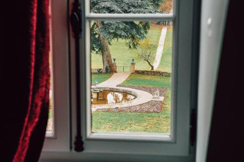 a window view of a garden with a fountain through it at Château Ecrin de Lumière in Campsegret