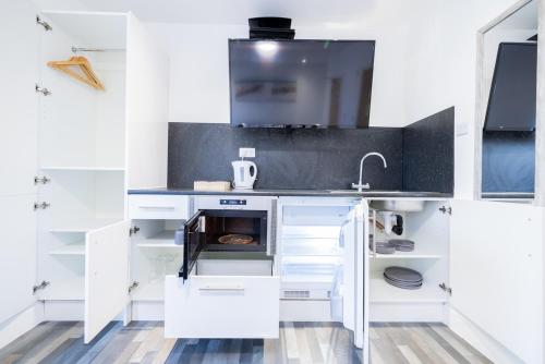 a kitchen with white cabinets and a sink at Hillcrest Studio Apartments in Cleethorpes