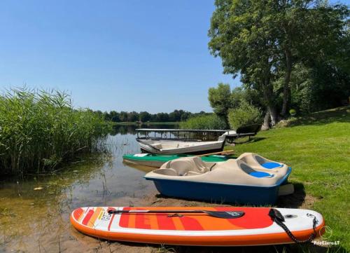 three boats sitting on the shore of a river at AGUONA ROYAL OASIS in Molėtai