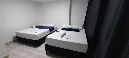 two beds in a room with black curtains at Hotel Caldas Real in Caldas