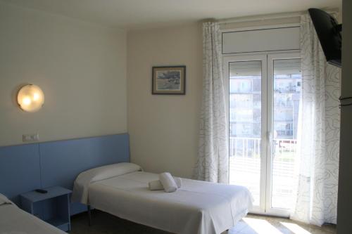 a bedroom with two beds and a large window at Hotel del Mar in Sant Feliu de Guíxols