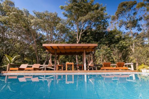 a swimming pool with a gazebo and chairs next to a swimming pool at Pousada Villa Pinhal in Santo Antônio do Pinhal