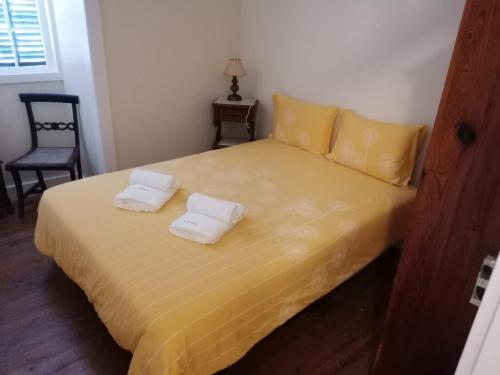 1 dormitorio con 1 cama amarilla y 2 toallas en A Casa da Matriz, en Madalena