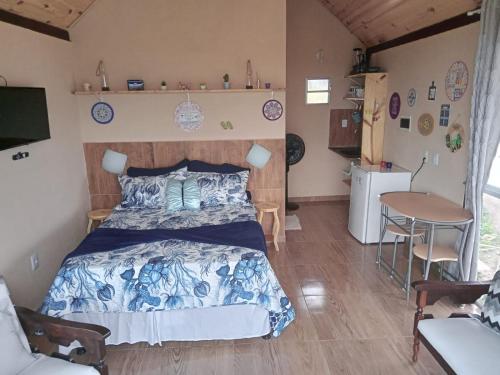 a bedroom with a bed and a table and chairs at Chalé Mirante da Pedra in Serra de São Bento