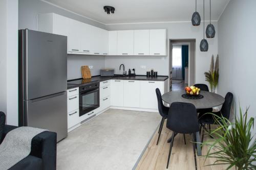 a kitchen with white cabinets and a table and chairs at Apartament Sopot Kamienny Potok Kujawska in Sopot