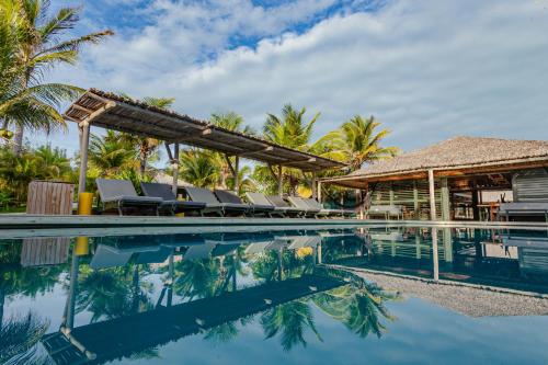 a pool at a resort with chairs and palm trees at Hotel VilaVeraTheresa in Fortim