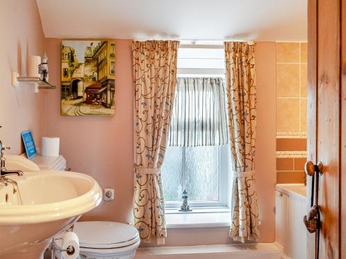 een badkamer met een wastafel, een toilet en een raam bij Dotty Cottage in Ellingham