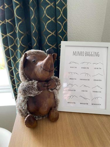 a stuffed teddy bear sitting on a table next to a sign at Clune House B&B in Newtonmore