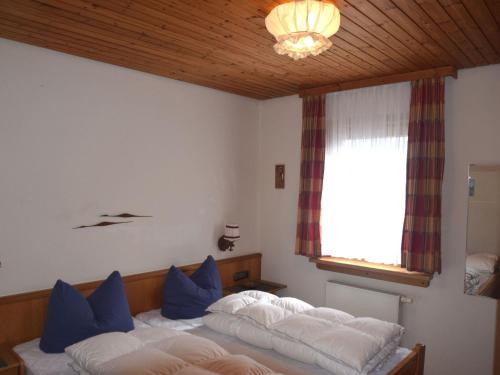 sypialnia z 2 łóżkami z niebieskimi poduszkami i oknem w obiekcie Weissensee holiday home w Füssen