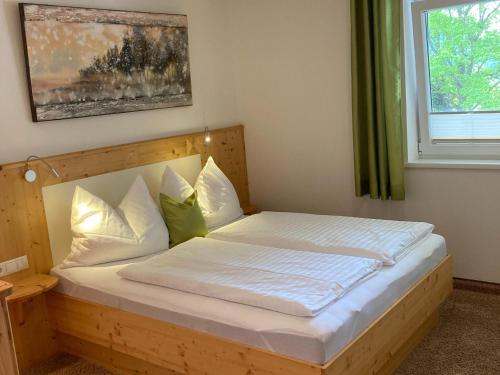 um quarto com uma cama de madeira com almofadas brancas e uma janela em Holiday apartment in Pinzgau with a large terrace em Mittersill