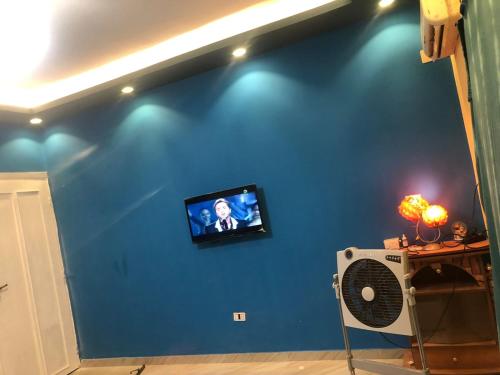 TV en una pared azul con ventilador en شقة مفروشة هاى سوبر لوكس بجوار سيتى ستارز, en El Cairo