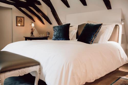 a bedroom with a white bed with blue pillows at Château Ecrin de Lumière in Campsegret