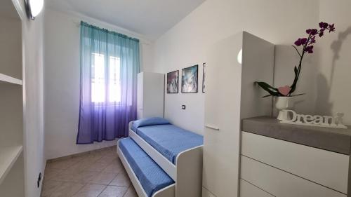 Zimmer mit 2 blauen Betten und einem Fenster in der Unterkunft Casa Iris in Capoliveri