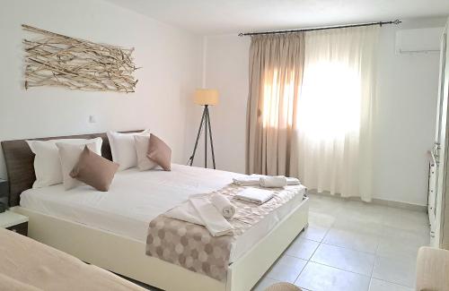 a white bedroom with a large bed and a window at Petrino Studios in Keramotí