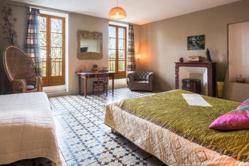 ein Schlafzimmer mit einem Bett, einem Tisch und einem Stuhl in der Unterkunft Le Relais de Tamaroque in Portel-des-Corbières