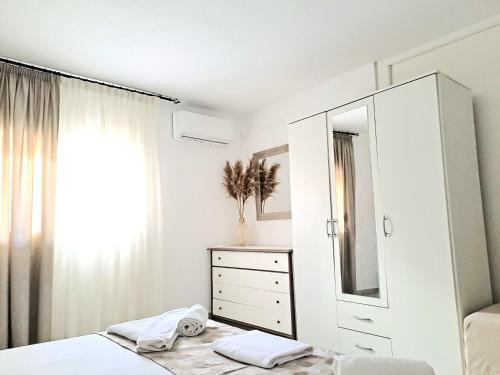 a white bedroom with a dresser and a mirror at Petrino Studios in Keramotí