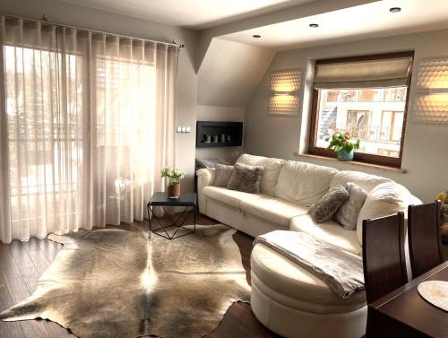 sala de estar con sofá blanco y ventana en Apart-Center Ogrody Górskie, en Zakopane