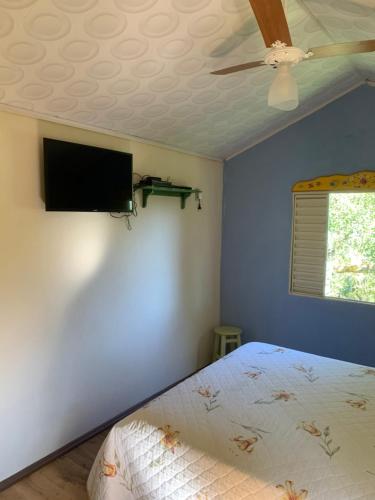 - une chambre avec un lit et un ventilateur de plafond dans l'établissement Fazenda Camping Cabral, à São Lourenço