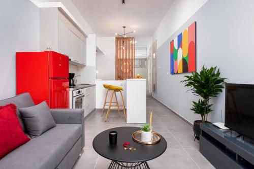 a living room with a couch and a kitchen with a red refrigerator at Theo's Cozy Apartment near Athens airport in Spata